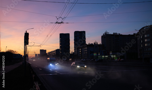 cars pierce the fog at sunset in the city with the light from the headlights © Ilia