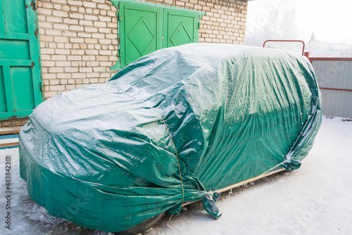 Car covered in winter. Sheltered car in winter. Tent for the car.