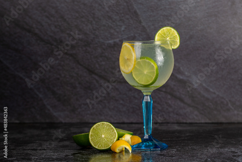 Alcoholic drink gin and tonic cocktail with lemon and ice on concrete background. space for text photo