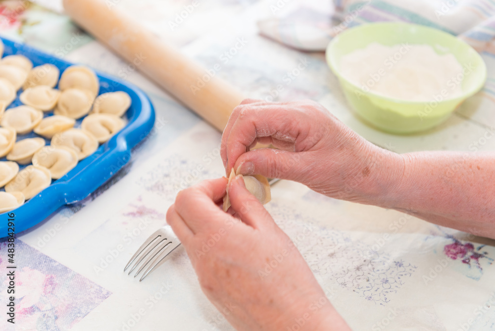 Sculpt dumplings with your hands. The woman is preparing food. Traditional Russian cuisine. Raw dumplings. Delicious homemade food. Sculpt dumplings with your hands. The woman is preparing food. Traditional Russian cuisine. Raw dumplings. Delicious homemade food.