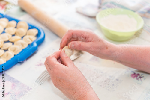 Sculpt dumplings with your hands. The woman is preparing food. Traditional Russian cuisine. Raw dumplings. Delicious homemade food.
