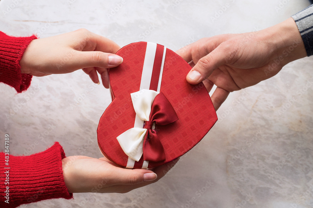 Valentine's Day concept. Happy man and woman in love presenting gifts to each other at a cafe. A young loving couple celebrating Valentine's Day in the restaurant. Valentine's Day concept. Happy man and woman in love presenting gifts to each other at a cafe. A young loving couple celebrating Valentine's Day in the restaurant.