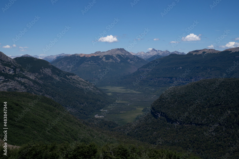 View of the mountains, valley and green forest, under a clear blue sky. 