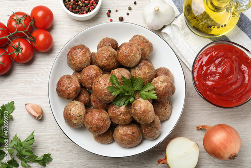 Tasty cooked meatballs with parsley on white wooden table, flat lay