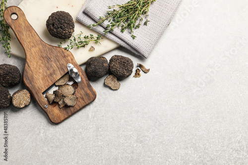 Fresh black truffles, slicer and thyme on grey table, flat lay. Space for text