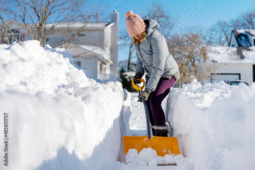 Canvas Print Woman shoveling snow out of driveway.