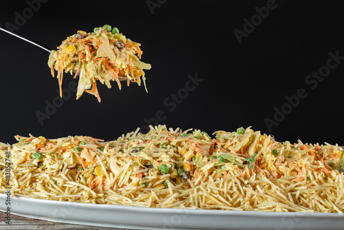 Spoon with Chicken salad. Salpicão is a typical Brazilian salad, made with shredded chicken, raisin, grated carrot, potato sticks and mayonnaise.