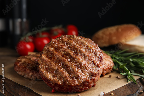 Tasty grilled hamburger patties with seasonings on wooden table, closeup