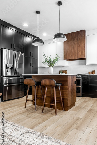 Midcentury modern kitchen with black and white cabinets, matte black fixtures, white quartz countertops and backsplash and walnut wood furniture interior design