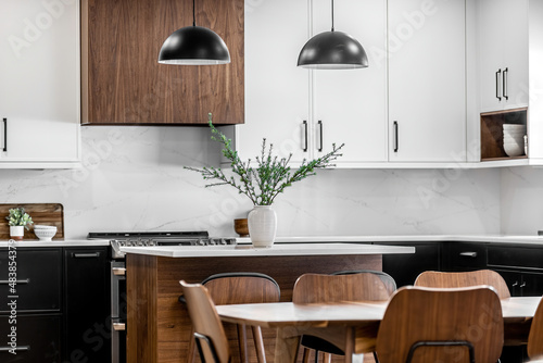 Midcentury modern kitchen with black and white cabinets, matte black fixtures, white quartz countertops and backsplash and walnut wood furniture interior design