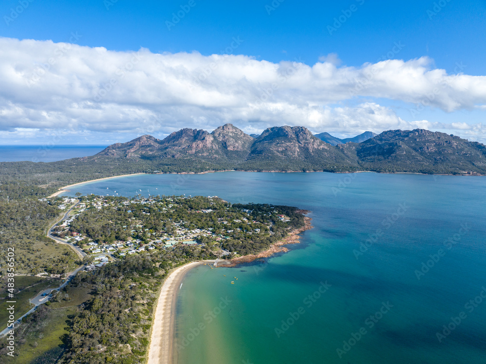 High angle aerial drone view of Coles Bay with Richardsons Beach and Hazards mountain range in the background, part of Freycinet Peninsula National Park, Tasmania, Australia. Muirs Beach in foreground