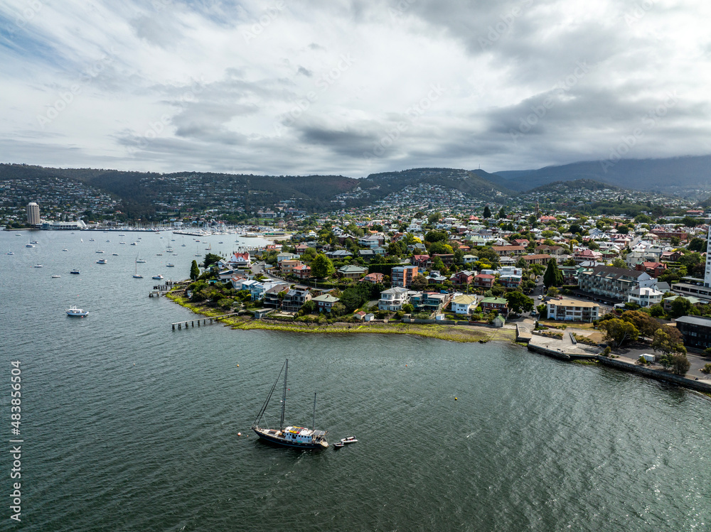 High angle aerial drone view of Battery Point, a waterfront residential suburb near the CBD of Hobart, capital city of the island and state of Tasmania, Australia. Sailboat in the foreground.