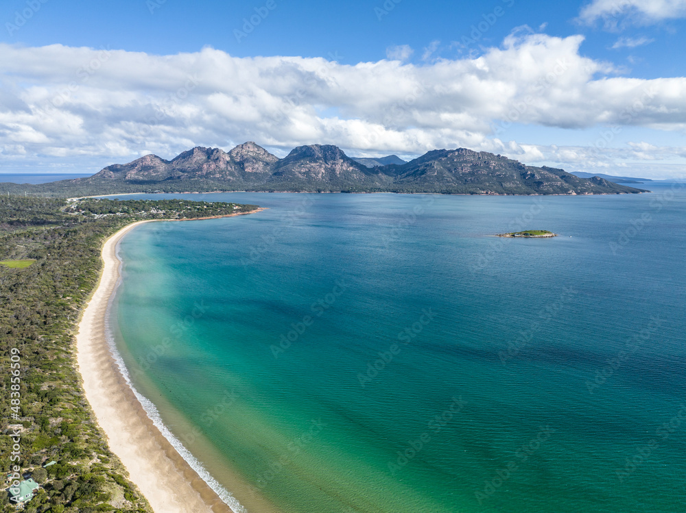 4k high angle aerial drone view of Muirs Beach near Coles Bay with the famous Hazards mountain range in the background, part of Freycinet Peninsula National Park, Tasmania, Australia.	