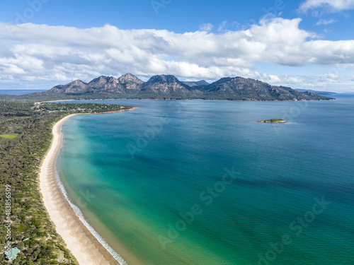 4k high angle aerial drone view of Muirs Beach near Coles Bay with the famous Hazards mountain range in the background, part of Freycinet Peninsula National Park, Tasmania, Australia. 