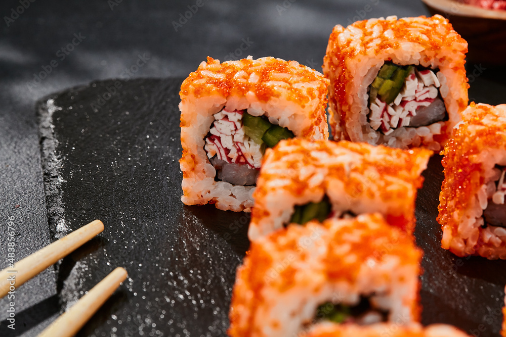 Maki sushi on dark stone table. California maki with tobiko. Sushi roll