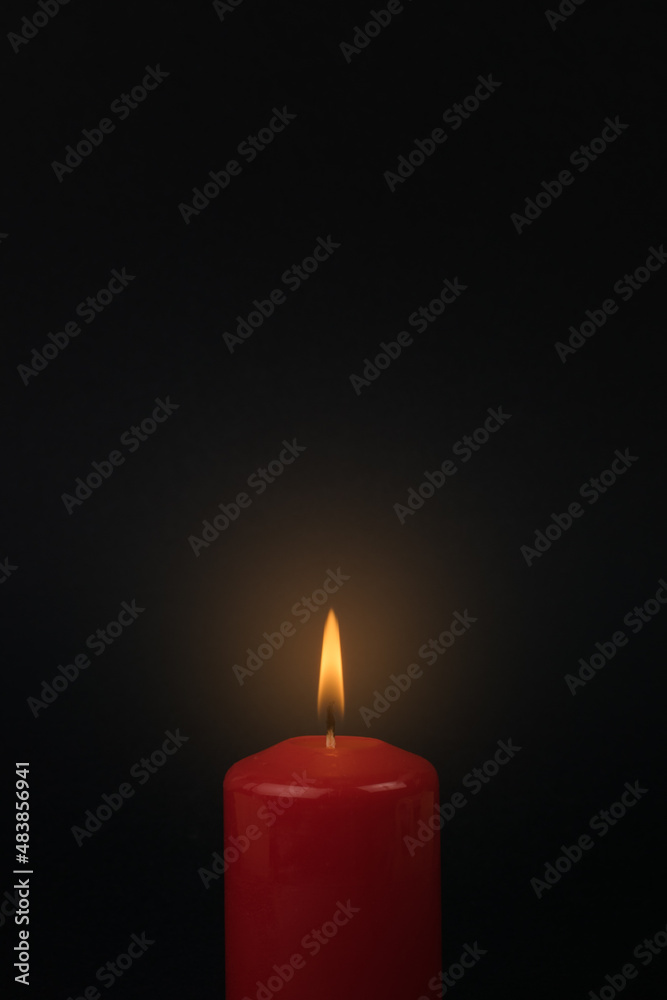 A bright burning candle on a black background. A bright burning candle on a black background.
