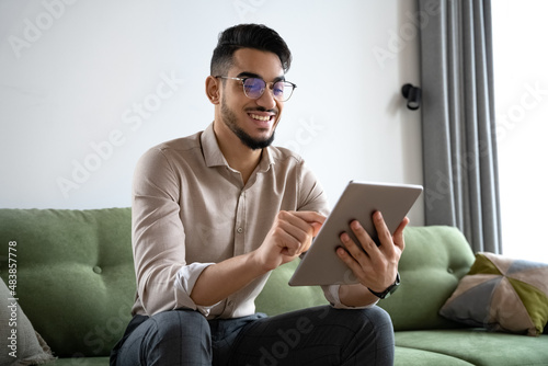 Young man using digital tablet computer sitting on sofa at home office photo