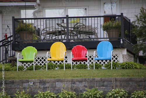 Green, yellow, red and blue vintage lawn chaires lined up ready to enjoy summer by the lake photo