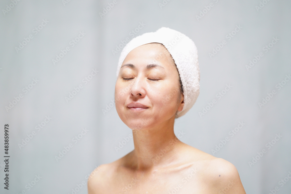 頭にタオルを巻いて目を閉じる素顔の中年女性 頭にタオルを巻いて目を閉じる素顔の中年女性