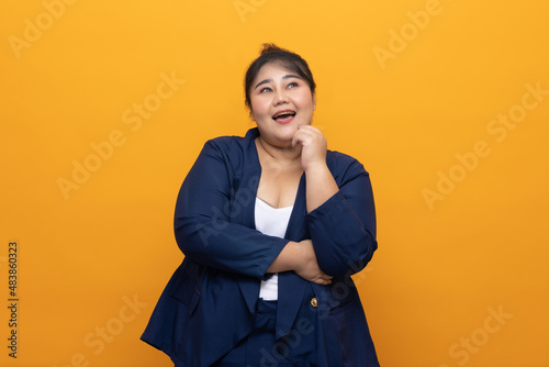 Happy young woman plus pose with isolated yellow background. Body positive plus size female lives happy and proud of herself. Business female smiling to camera. © Chanakon