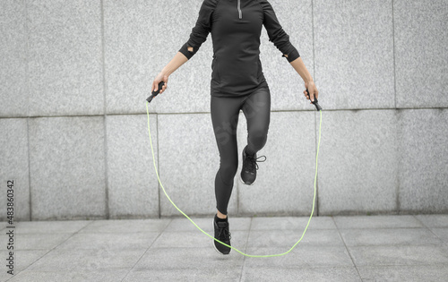 Fitness woman rope skipping against city wall photo