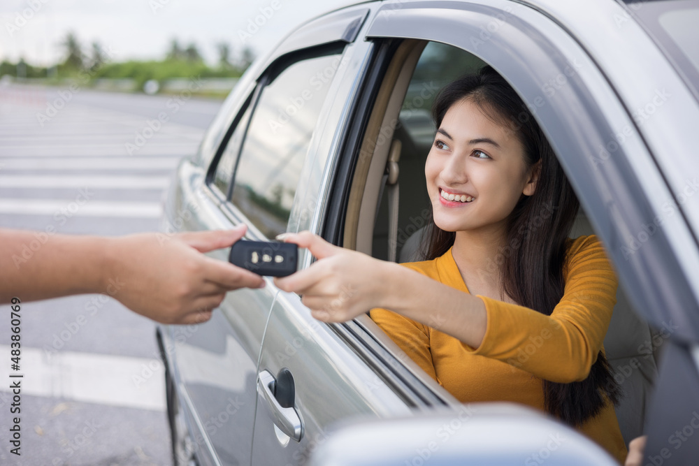 Young beautiful asian women buying new car. she very happy and excited. Sit in and getting car key. Smiling female driving vehicle on the road on a bright day