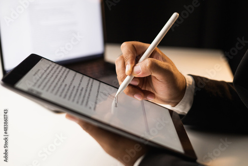 Close up businessman hand electronic Signature on Tablet by Stylus. Write business agreement of contract. Man signing contract on tablet. Business and technology concept. photo