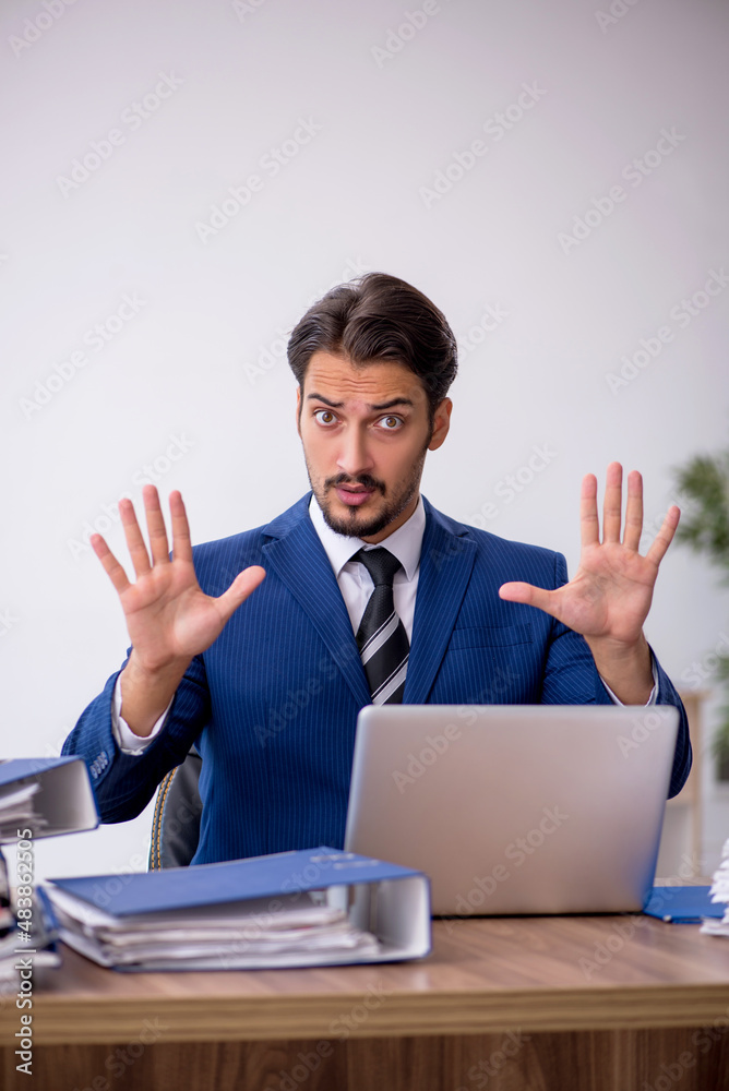 Young male employee and too much work in the office Young male employee and too much work in the office