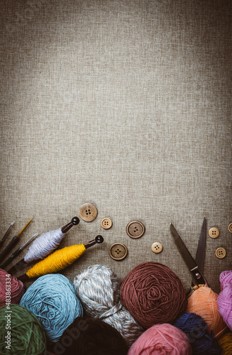 Panoramic view of composition with knitting accessories: balls of wool yarn, set of knitting needles, hooks, and other knit tools on wooden background. Long banner, top view, copy space, flat lay.