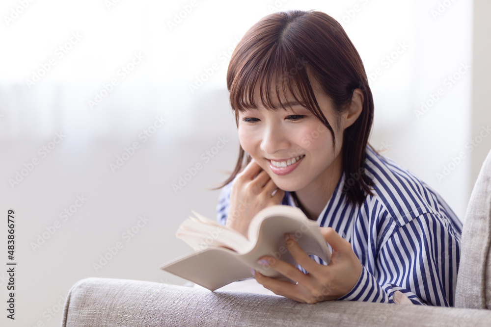 ソファに寝転んで読書する女性 ソファに寝転んで読書する女性