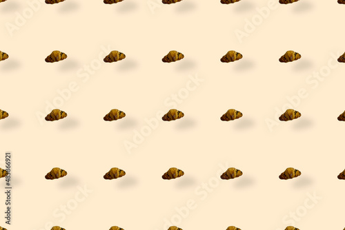 Colorful pattern of croissants on light orange background with shadows. Top view. Flat lay. Pop art design