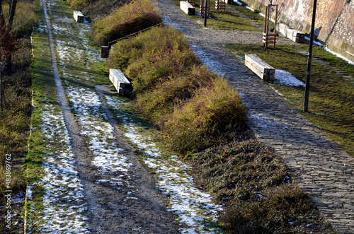 stone path in the garden with terraced levels and stone nature paths with snow-covered lawns. garden bench in the shape of a beam prism side by side in a lawn park architecture, longevity, cheap photo