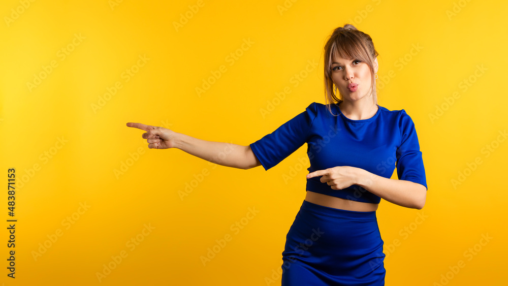 Funny Girl pointing index fingers aside on the left and looking at camera on yellow background. Young woman showing from forefingers indicates direction over. Inviting use link or try-out product. Funny Girl pointing index fingers aside on the left and looking at camera on yellow background. Young woman showing from forefingers indicates direction over. Inviting use link or try-out product.