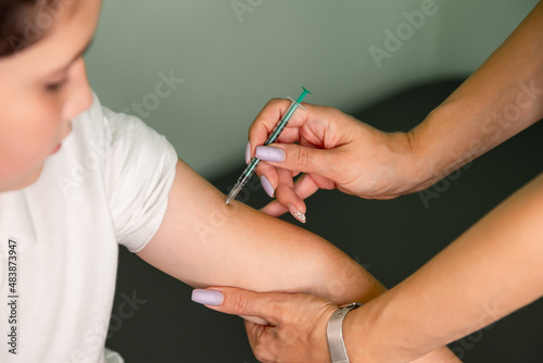 Nurse with syringe vaccinating teenager with anti-virus vaccine injection in hospital. Vaccinations for children, immunization, disease prevention. Vaccination and covid prevention. Injecting COVID-19