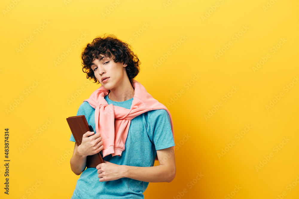 curly guy education with notepad hand gesture yellow background curly guy education with notepad hand gesture yellow background