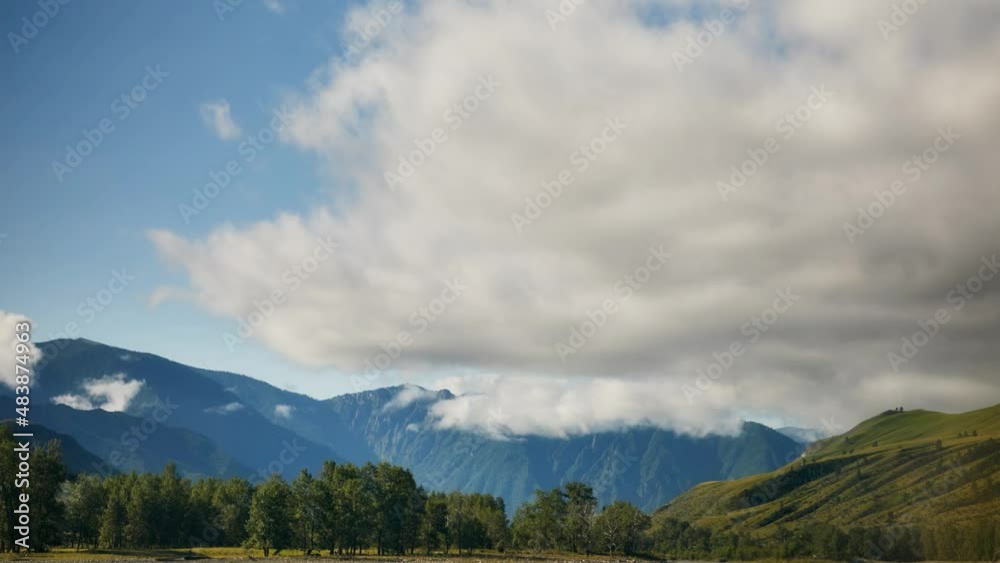 Timelapse. Summer landscape of Altai mountains with a green meadow and trollius flowers in the foreground Timelapse. Summer landscape of Altai mountains with a green meadow and trollius flowers in the foreground