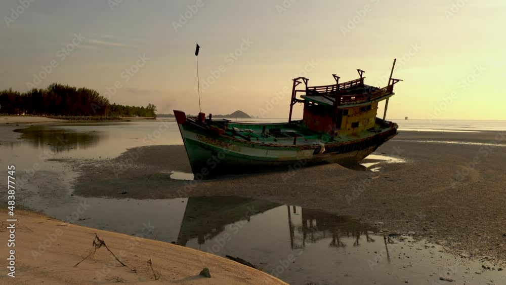 Passing old fisher boat wreck stranded on sandy shore - Sunset scenes of boat wreck along shore side - Nathon harbour - Koh Samu Island in Thailand Passing old fisher boat wreck stranded on sandy shore - Sunset scenes of boat wreck along shore side - Nathon harbour - Koh Samu Island in Thailand