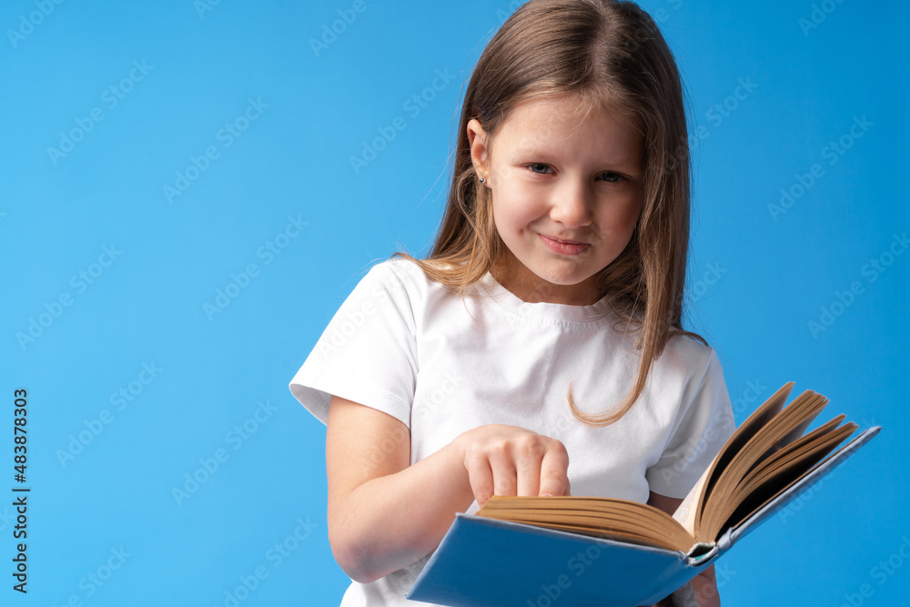 Little beautiful smiling girl holding book against blue background Little beautiful smiling girl holding book against blue background