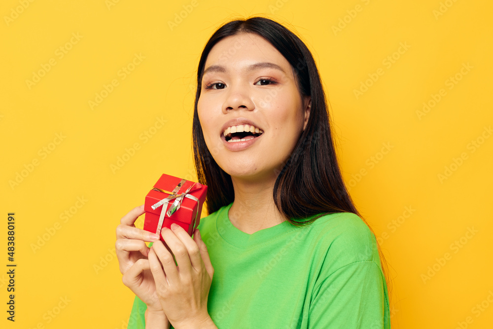 Portrait Asian beautiful young woman with a small gift box holiday yellow background unaltered Portrait Asian beautiful young woman with a small gift box holiday yellow background unaltered
