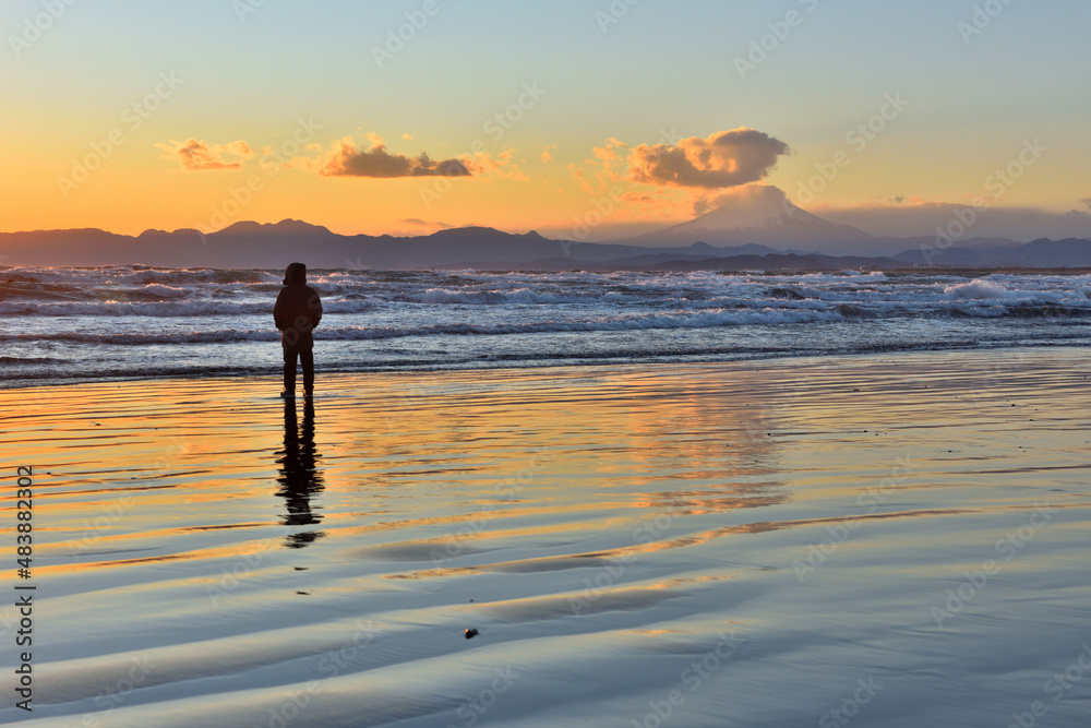 片瀬西浜海岸の夕陽と波打ち際で遊ぶ子供たち