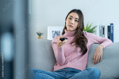 Fotografija Asian unhappy young beautiful woman watch movie on television at home