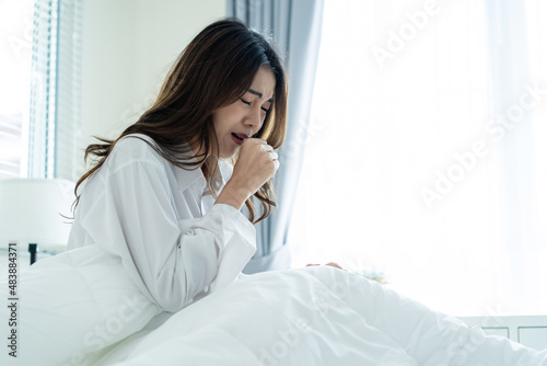 Asian beautiful sick girl in pajamas getting up from sleep in bedroom. 