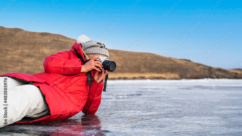 Obraz premium Tourist photographer with a camera on the ice of Lake Baikal