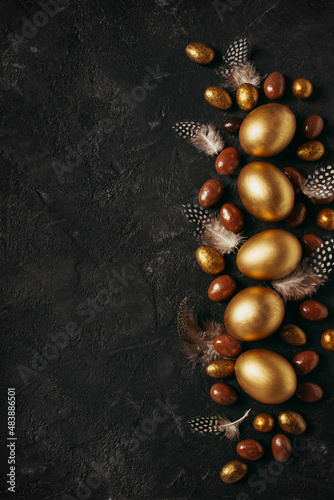 Canvas Print Happy easter concept flat lay with gold eggs and feather on black background