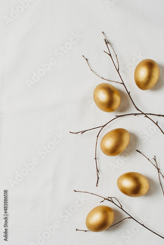 Happy easter concept flat lay with gold eggs and feather on white background