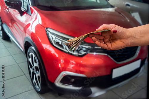 beautiful young female hands with manicure holding a large amount of euro banknotes on the background of cars