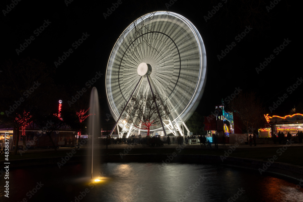 white Ferris wheel in full swing at night. image taken with long exposure.