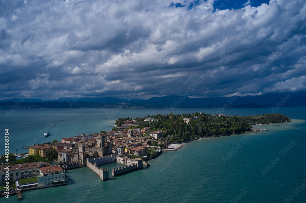 Rocca Scaligera Castle in Sirmione.  Aerial view on Sirmione sul Garda. Italy, Lombardy.  Panoramic view at high altitude. Cumulus clouds over the island of Sirmione. Aerial photography with drone.