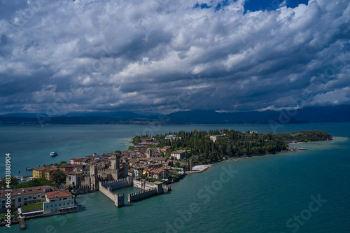 Rocca Scaligera Castle in Sirmione. Aerial view on Sirmione sul Garda. Italy, Lombardy. Panoramic view at high altitude. Cumulus clouds over the island of Sirmione. Aerial photography with drone.