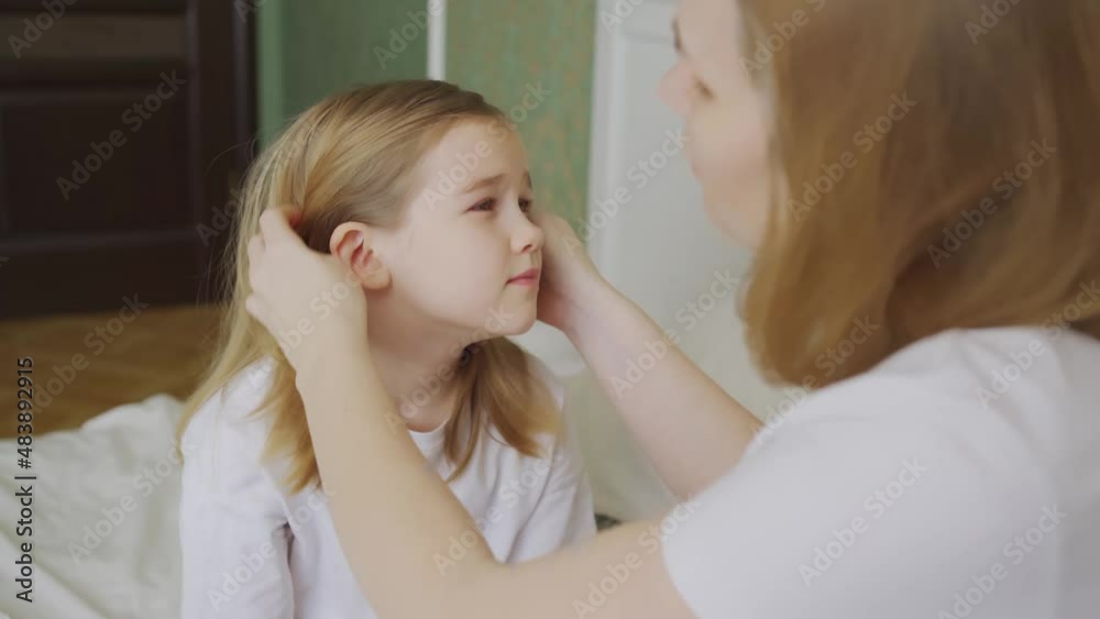 daughter complains about pain in the ear and mother examines her. daughter complains about pain in the ear and mother examines her.